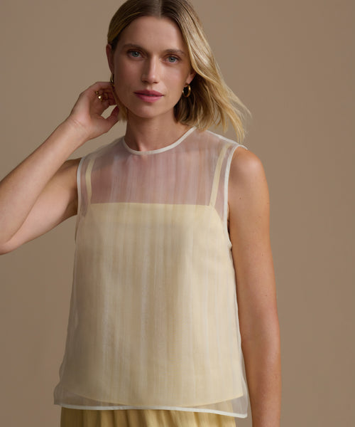 Woman wearing a yellow cora top against a beige background