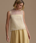 Woman wearing a yellow cora sleeveless top and skirt against a beige background