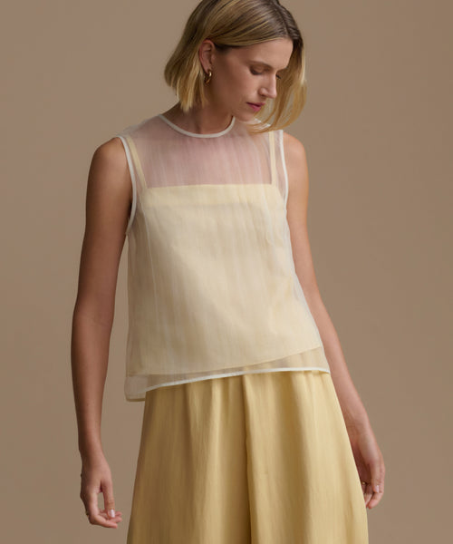 Woman wearing a yellow cora sleeveless top and skirt against a beige background