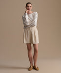 Woman wearing a striped shirt and beige shorts against a beige background