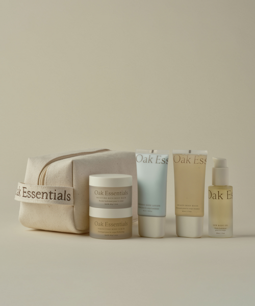 The Travel Body Routine is showcased: a beige Oak Essentials toiletry bag alongside TSA-approved skincare minis—a jar, two squeeze tubes, and a pump bottle with minimalist labels—ideal for your travel body care on a neutral background.