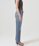 A person stands in profile against a plain background, wearing a sleeveless black ribbed top, the 90s Jean by AGOLDE crafted from organic cotton, and black heeled sandals.