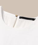 Close-up of the Blair Dresss back neckline, showing a round collar, small keyhole with a gold button, black label, and subtle linen texture—an ideal choice for your spring wardrobe.