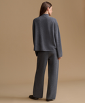 A model shown from the back wearing a dark gray knit sweater and matching wide-leg trousers against a solid beige studio background.
