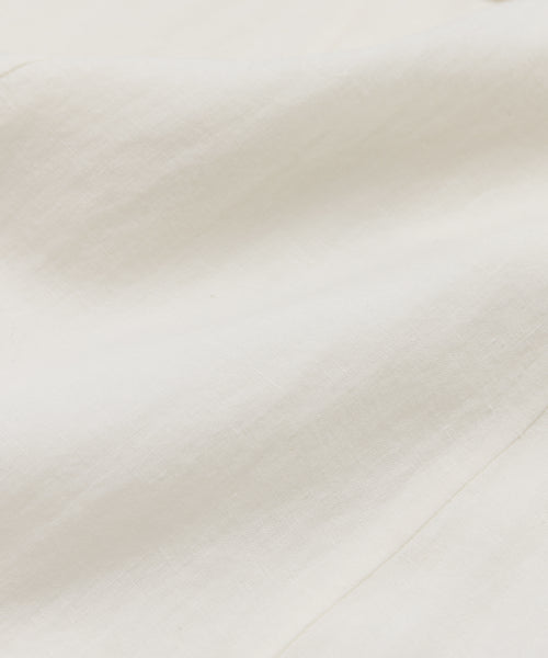 Close-up of the Callan Dress in white, featuring a smooth, slightly wrinkled fabric with soft folds. Its timeless elegance and classic style make it a true closet staple, beautifully highlighted by natural light.