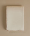 A cream-colored blanket with a stitched border, photographed flat on a matching beige background.