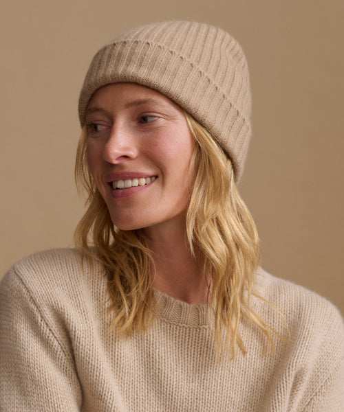 Woman wearing an oatmeal color cashmere sweater with a matching ribbed beanie.
