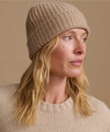 Woman wearing an oatmeal color cashmere sweater with a matching ribbed beanie.