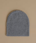 A gray ribbed knit beanie hat photographed flat against a solid beige background.