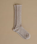 A pair of ribbed knit crew socks in a heathered taupe-beige color, displayed against a solid beige background.