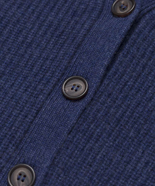 Close-up of the Cropped Cashmere Cocoon Cardigan in blue, showcasing its ribbed texture and dark buttons arranged vertically along the buttoned seam.