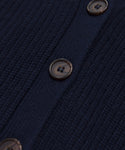 Close-up of navy blue knit fabric from the Cropped Cashmere Cocoon Cardigan, showing a vertical line of brown plastic buttons sewn onto a smooth, solid strip.