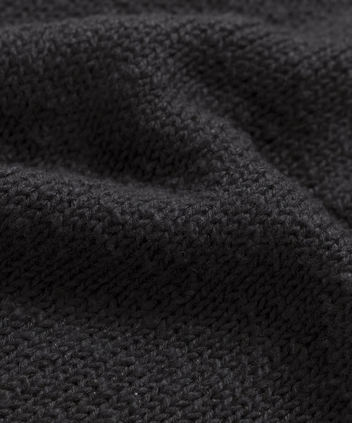 Close-up of the Cruise Cocoon Crewnecks textured, dark gray oversized knit fabric with visible stitching and gentle folds, giving it a soft and cozy look.