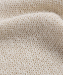 Close-up of the Cruise Cocoon Crewneck’s textured, cream-colored lightweight knit fabric with visible stitches and soft, wavy folds.