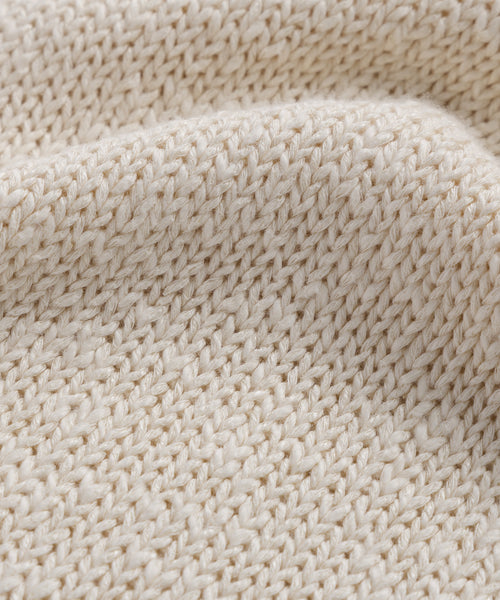 Close-up of the Cruise Cocoon Crewneck’s textured, cream-colored lightweight knit fabric with visible stitches and soft, wavy folds.