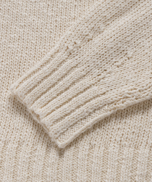 Close-up of the Cruise Cocoon Crewneck, featuring its cream color, textured knit pattern, and ribbed cuff on the lightweight sleeve.