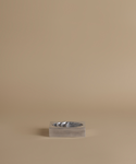 A small rectangular metallic tray or dish with a wavy interior, centered on a warm beige studio background.