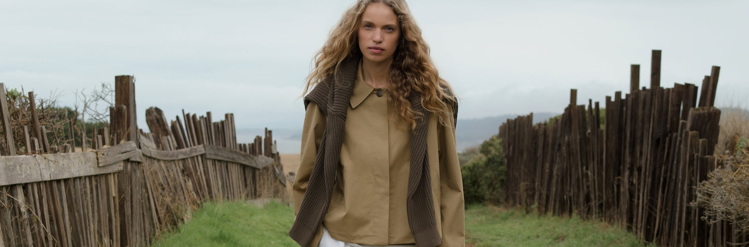 Woman standing in a field with wooden fences and a scenic background