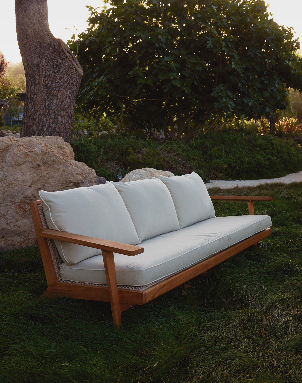 Wooden outdoor sofa with white cushions in a garden setting