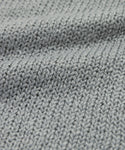 Close-up of the Foster Cotton Sweater, crafted from soft organic Tanguis cotton in light gray, featuring a textured ribbed knit and wavy folds.