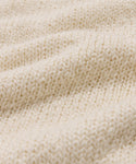 Close-up of the cream Foster Cotton Sweater, featuring a textured knit and soft, wavy folds—crafted from organic Tanguis cotton for exceptional comfort.