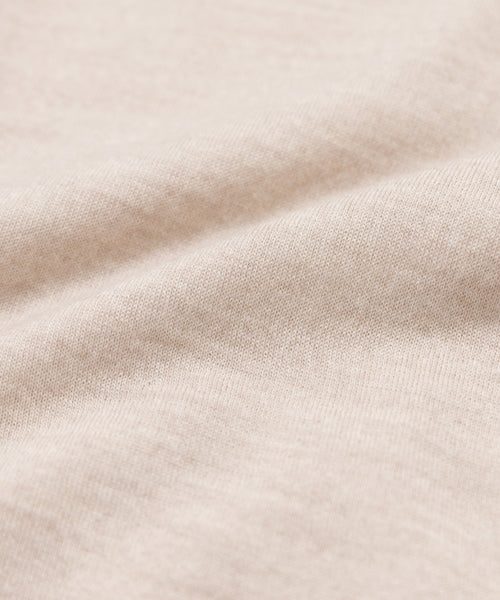 Close-up of the Grayson Pullover’s soft, light beige fabric with subtle texture and gentle folds, evoking a cozy warm-weather sweater. The smooth, slightly fuzzy surface highlights the material’s inviting comfort.