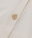 Close-up of the Mira Cardigan in ivory, showcasing a single round translucent button fastened through its knitted fabric.