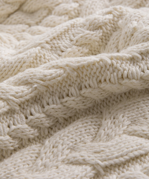 Close-up of the Cotton Cable Half Zip, showcasing its cream color, soft and thick cable knit pattern, and intricate detailing.