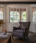 A living room with an accent chair, wood coffee table and a lit candle. 