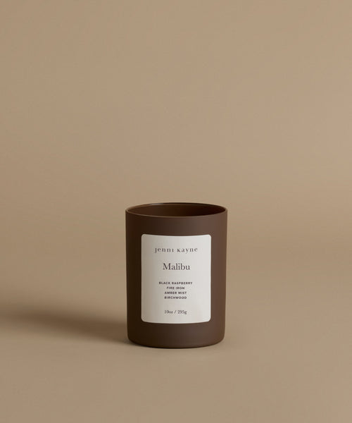 A glass candle by Jenni Kayne in the scent Malibu against a beige background.