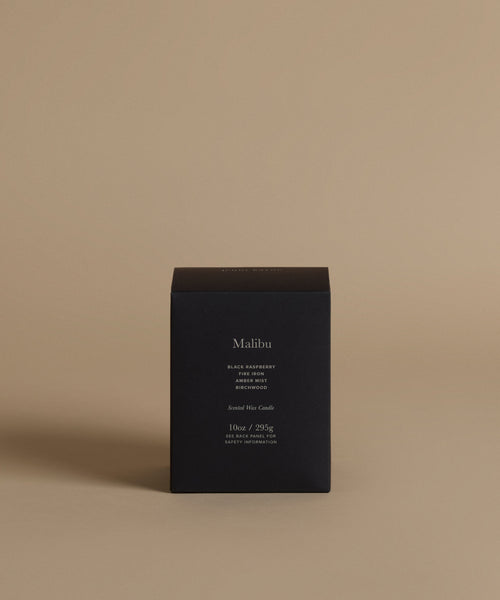 A candle box with the scent Malibu across the front against a beige background.