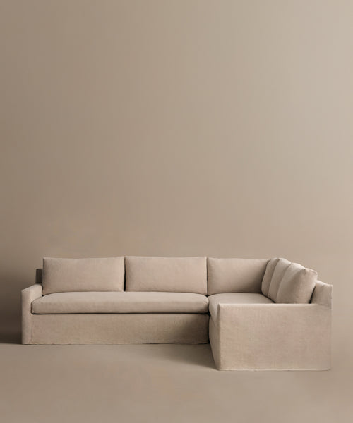 The Harbor Sectional is an L-shaped sofa in beige Belgian flax linen, featuring three back cushions and a minimalist design, shown with a matching beige background.