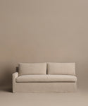 The Harbor Sectional is a minimalist Belgian flax linen sofa with two cushions and a left armrest, shown against a matching beige backdrop. Part of the Jenni Kayne Furniture collection.