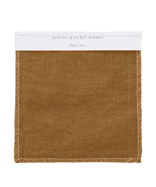 A Fabric Swatch Pine Linen in brown with white edge stitching, labeled jenni kayne home and Pine Linen on a white card at the top.