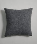 The Alpaca Basketweave Pillow, shown in dark gray with a square shape and slightly rounded corners, features a soft, fuzzy texture and is displayed against a plain light gray background.
