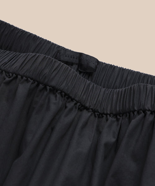 Close-up of the Lauren Skirt’s black waistband with gathered fabric and an inner black tag, set against a beige background.
