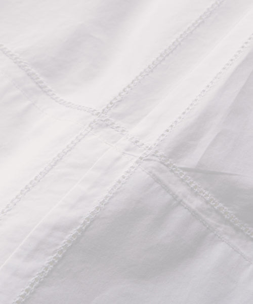 Close-up of the Lauren Skirt—white cotton with crisp, smooth fabric. Intersecting stitched seams create a grid pattern, complete with visible thread details. A true wardrobe staple for effortless style.