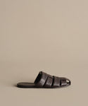 The Leather Camilla Mule is a dark brown, fisherman-inspired slide featuring wide woven leather straps and an open toe, shown against a plain beige background.