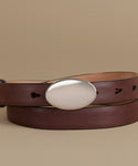 A dark brown leather belt with a large, polished silver oval buckle, neatly coiled on a solid beige background.