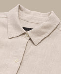 A close-up of the Linen Colby Shirt, this summer piece has a pointed collar and two cream buttons, showcased on a neutral background.
