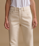A model wearing a white t-shirt with cream color jeans in a studio.