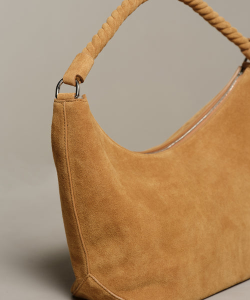 A close-up of the Medium Crescent Bag, crafted in tan suede with a twisted handle and silver hardware, made in Italy and shown against a neutral background.