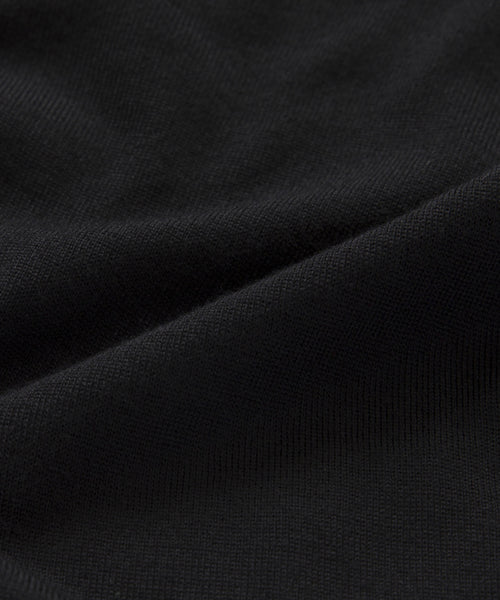 A close-up of black merino wool fabric reveals soft folds and a subtly textured surface with gentle shadows—ideal for the Merino Tank, offering a cozy and comfortable base layer.