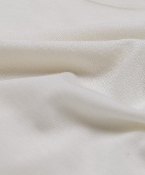 A close-up of soft, white merino wool with natural folds and a smooth, slightly textured surface—perfect for the Merino Tank as a comfortable base layer.
