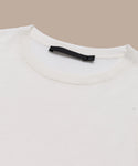 A close-up of a plain white Merino Tank laid flat on a beige surface, highlighting the collar and black label inside the neckline—an ideal base layer for any outfit.