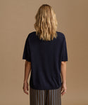 A model wearing a navy blue tee with stripe pants against a beige background.