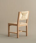 The Montecito Dining Chair in Warm Oak features a handwoven Danish paper cord seat and backrest, shown angled slightly left against a plain beige background.