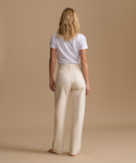 Model wearing cream color jeans with a cream t-shirt against a beige studio background.