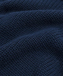 Close-up of dark blue textured fabric from the Oversized Cotton Fisherman, showcasing a waffle-knit pattern with small raised squares and soft, wavy folds—ideal for cozy womens knitwear.