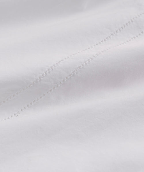 Close-up of Italian washed poplin on the Peninsula Dress: two parallel rows of small, evenly spaced decorative holes run diagonally, adding a subtle textured pattern—perfect for a classic white sundress.